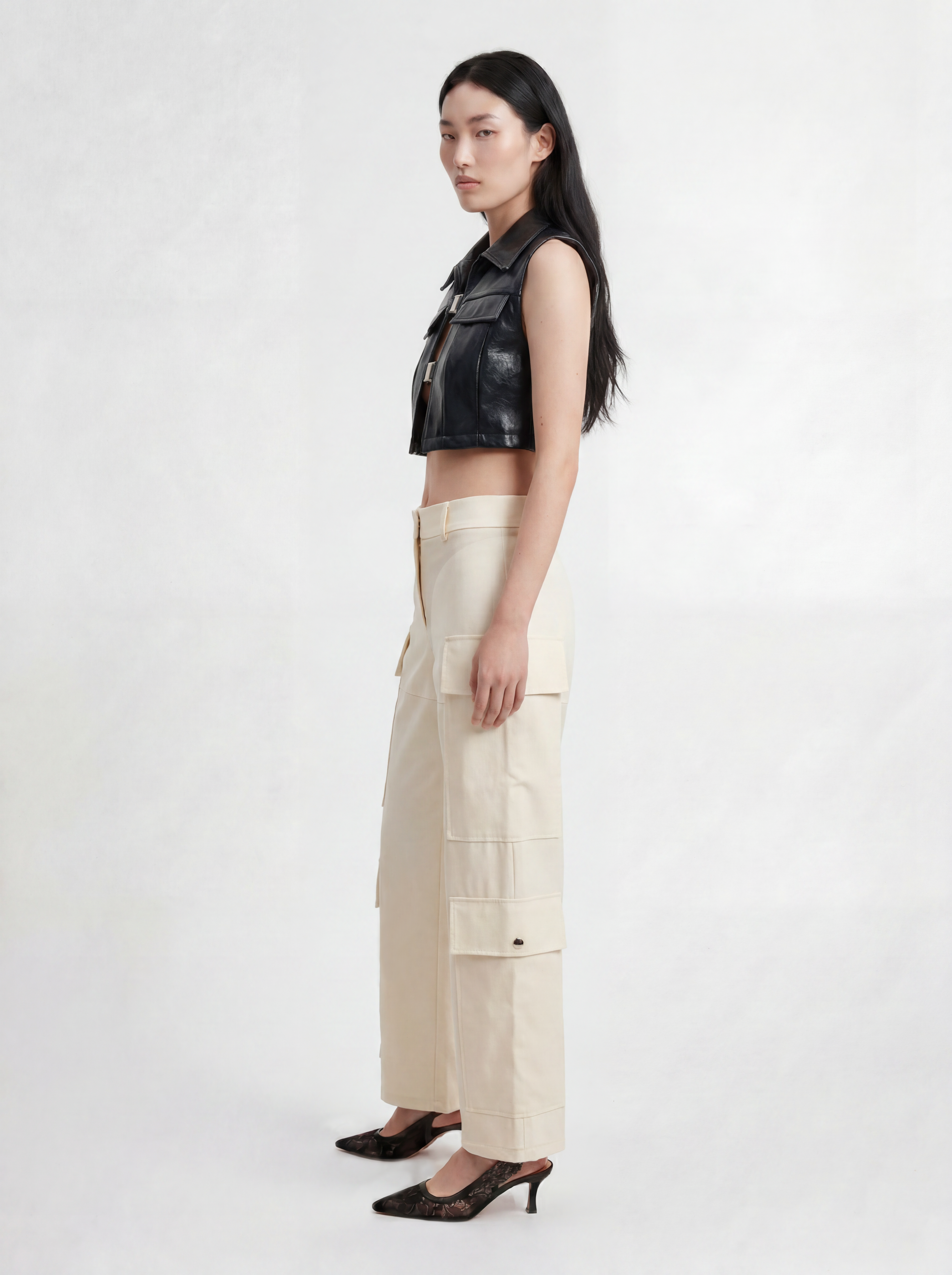 Side view of model wearing IL CARGO TRASPARENTE by ORNELLA COLICCHIO, styled with TOP OCEANO CON FIBBIE, looking into the camera and showing the cargo pockets and transparent technical fabric
