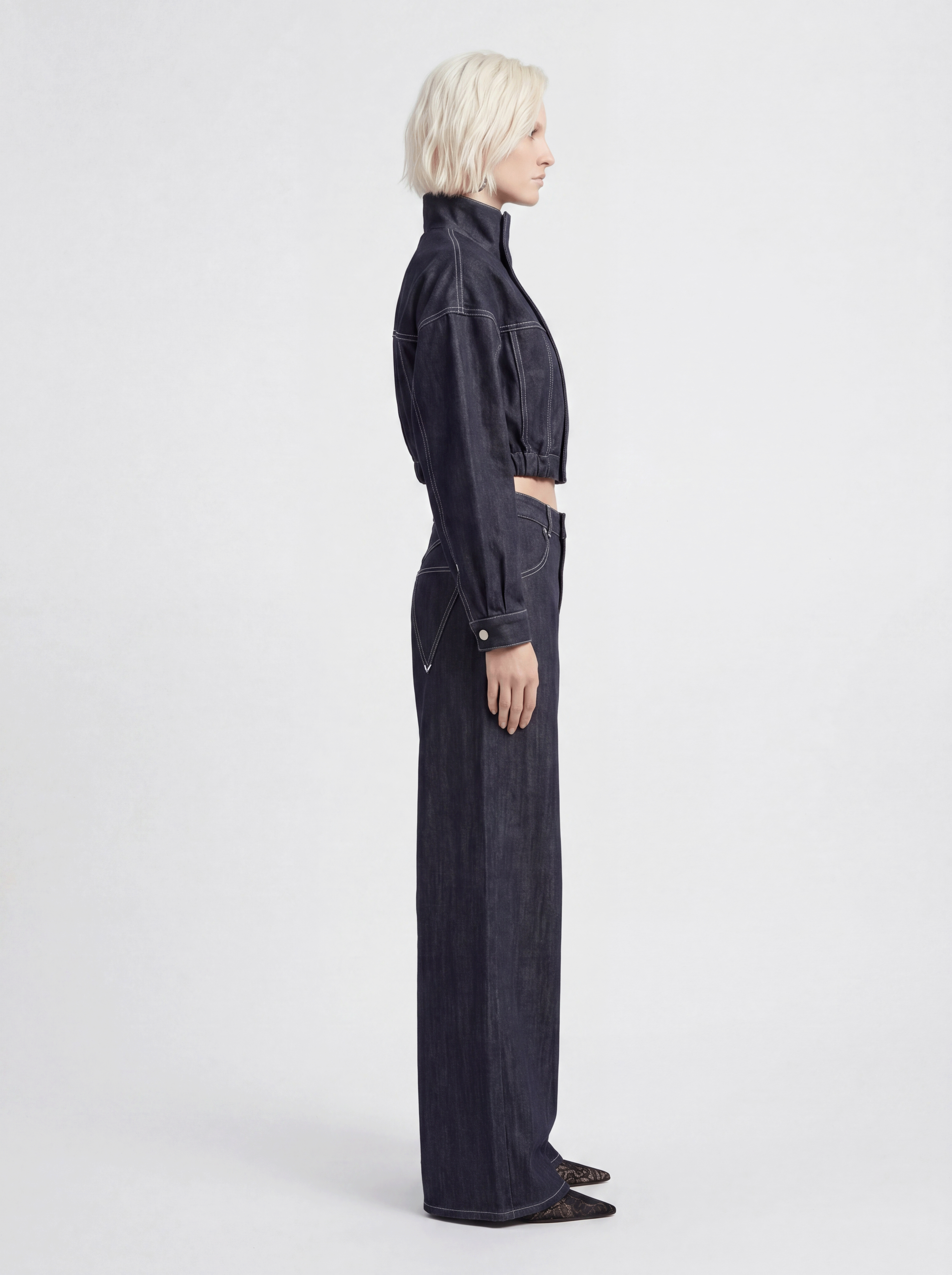 Side view of model wearing LA GIACCA CORTA IN DENIM and IL DENIM TRIANGOLO by ORNELLA COLICCHIO, showing the cropped fit of the denim jacket and the relaxed fit of the jeans