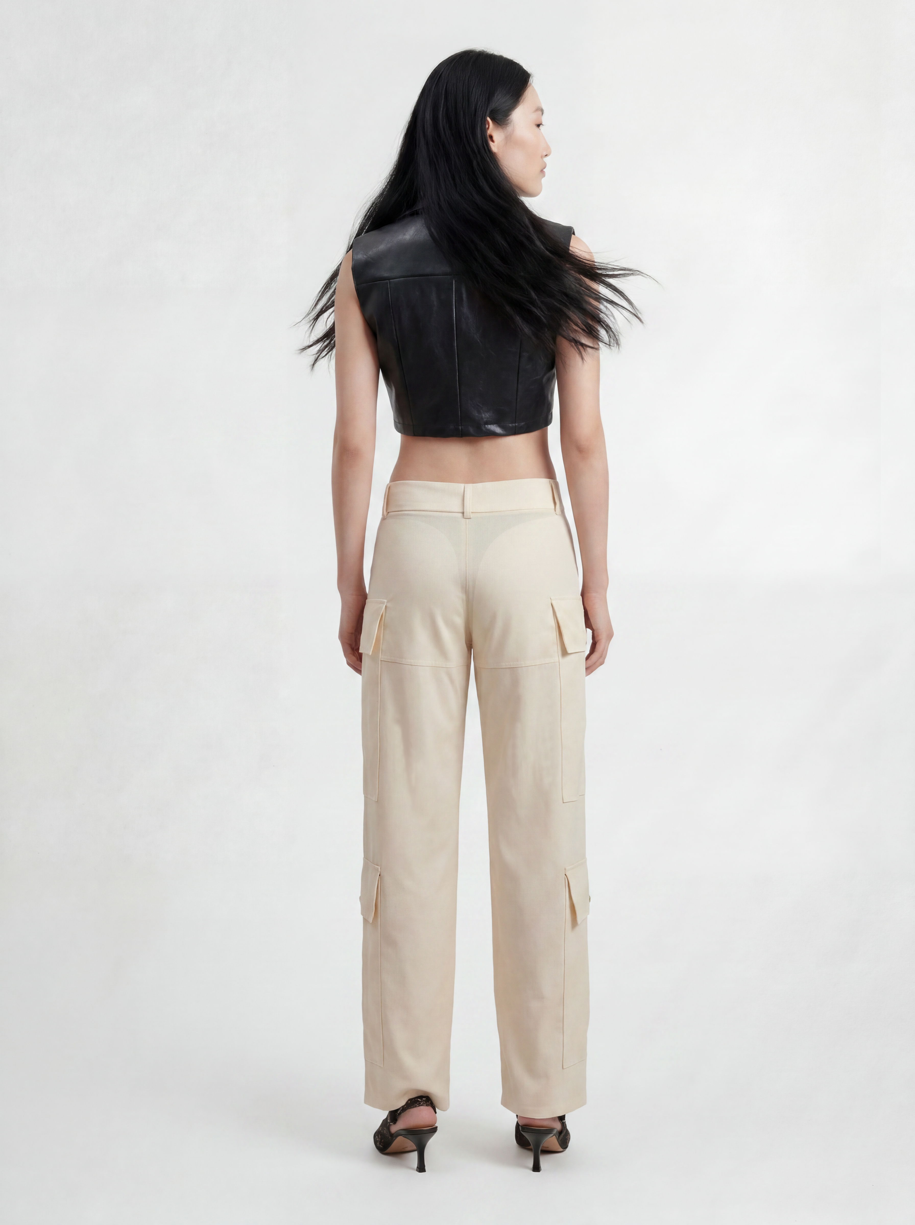 Back view of model wearing IL CARGO TRASPARENTE by ORNELLA COLICCHIO, styled with TOP OCEANO CON FIBBIE, showing the transparent technical fabric, wool fabric and material contrast