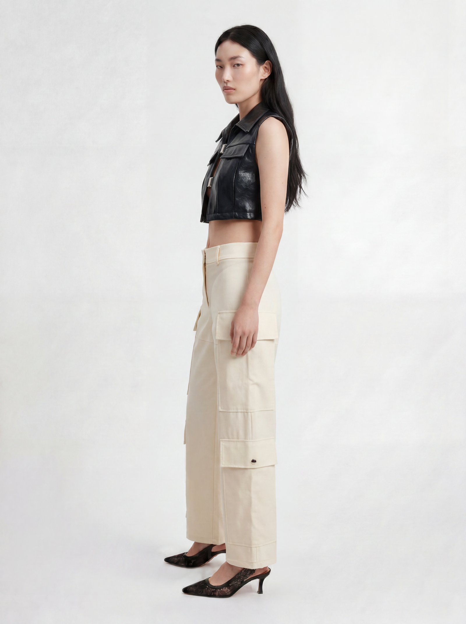 Side view of model wearing IL CARGO TRASPARENTE by ORNELLA COLICCHIO, styled with TOP OCEANO CON FIBBIE, looking into the camera and showing the cargo pockets and transparent technical fabric