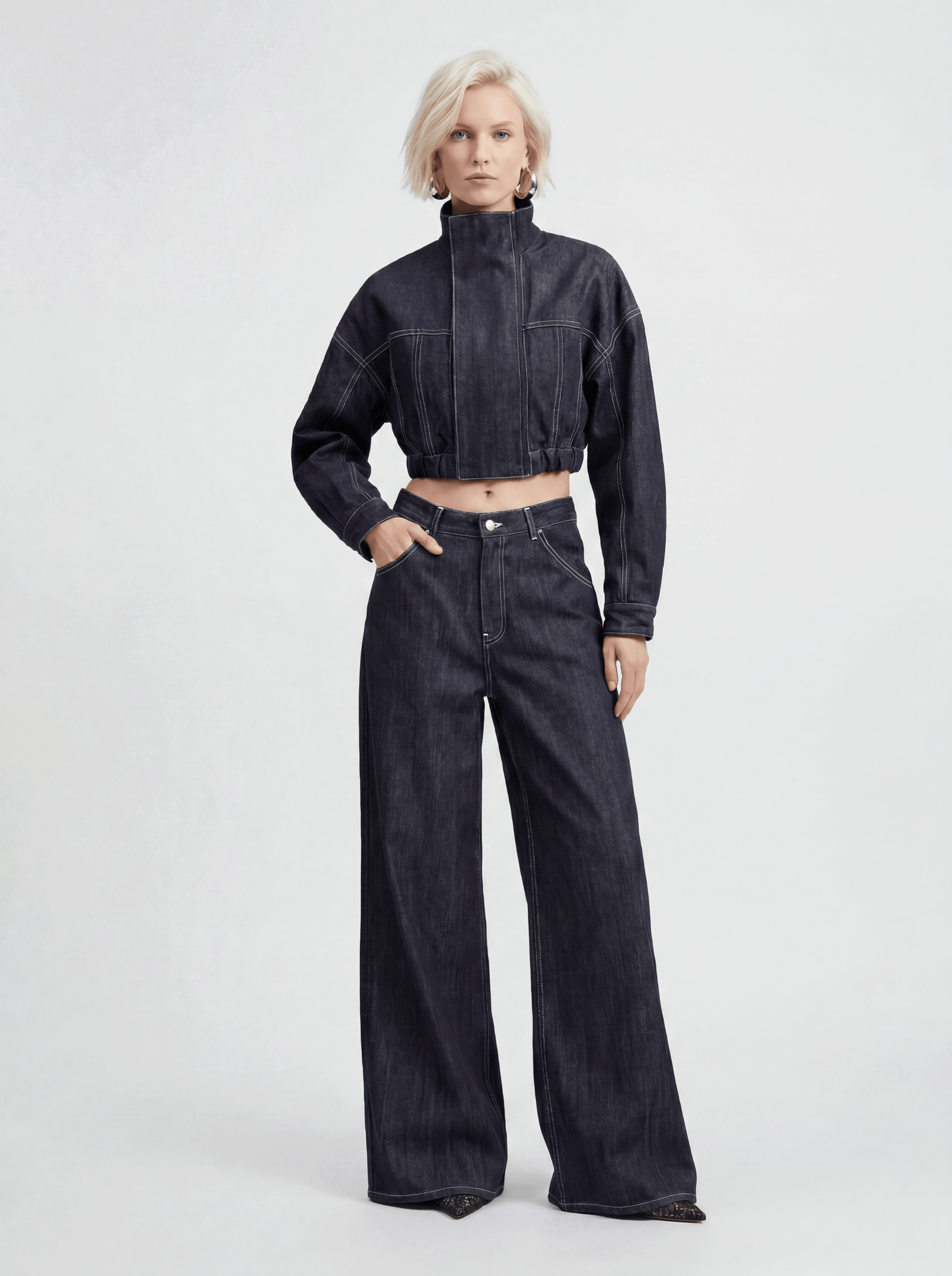 Front view of model wearing LA GIACCA CORTA IN DENIM and IL DENIM TRIANGOLO by ORNELLA COLICCHIO, looking directly into the camera and showing the cropped denim jacket with Triangolo jeans