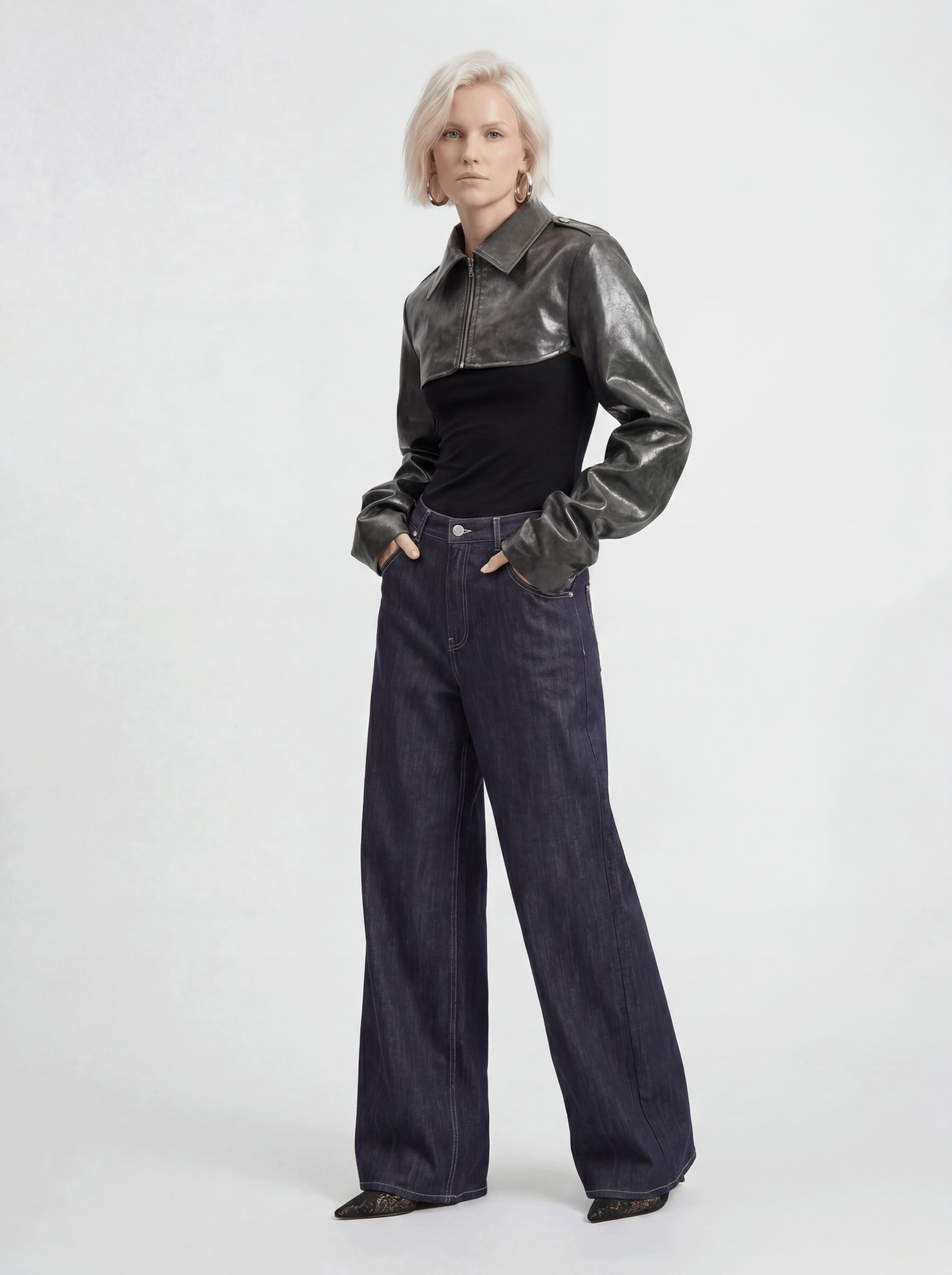 Front view of model wearing LA GIACCA CORTA SCULTURA by ORNELLA COLICCHIO with IL DENIM TRIANGOLO, slightly turning the upper body with both hands lightly in the pockets and looking into the camera
