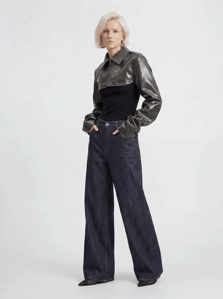Front view of model wearing LA GIACCA CORTA SCULTURA by ORNELLA COLICCHIO with IL DENIM TRIANGOLO, slightly turning the upper body with both hands lightly in the pockets and looking into the camera