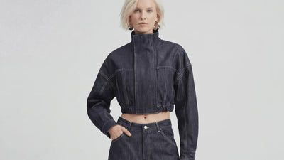 Video of model wearing LA GIACCA CORTA IN DENIM and IL DENIM TRIANGOLO by ORNELLA COLICCHIO, walking toward the camera, turning and showing a close view of the triangular back pockets