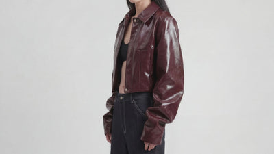 Video of model wearing LA GIACCA CORTA BORDEAUX by ORNELLA COLICCHIO, with the camera moving along the sculptural sleeves before she looks into the camera