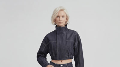 Video of model wearing LA GIACCA CORTA IN DENIM by ORNELLA COLICCHIO, walking toward the camera to reveal a close front view with high collar and white topstitching